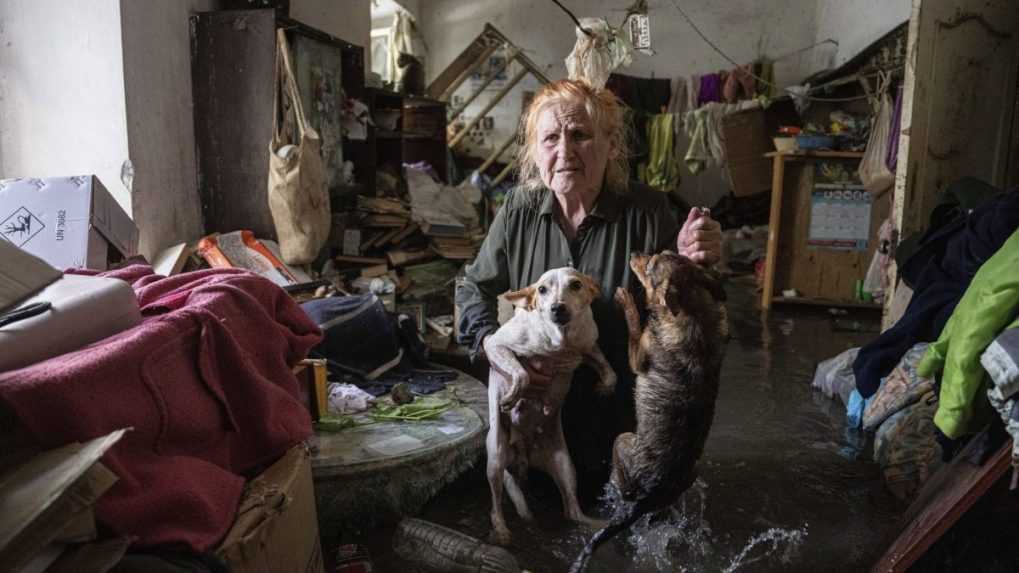 Miestna obyvateľka Tetiana drží svojich psov vo svojom dome, ktorý bol zaplavený po výbuchu Kachovskej priehrady.
