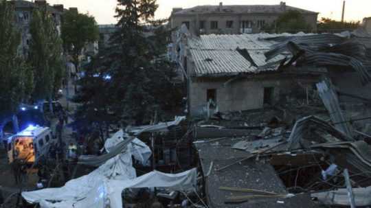 Ľudia odpratávajú trosky zo zničenej reštaurácie RIA Pizza po ruskom raketovom útoku v meste Kramatorsk.