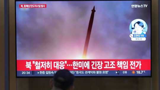 Osoba na železničnej stanici v Soule sleduje správy o odpaľovaní balistických striel Pchjongjangom.