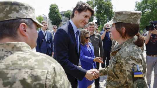 Kanadský premiér Justin Trudeau podáva ruku ukrajinskej vojačke.
