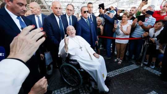 Na snímke pápež František po prepustení z nemocnice na invalidnom vozíku a okolo neho veriaci, členovia ochranky a novinári.