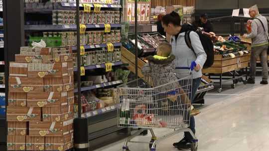 Na snímke žena s dieťaťom v potravinách. dieťa sedí v nákupnom košíku
