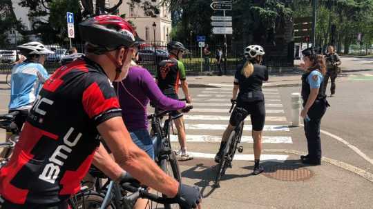 Na snímke policajtka usmerňuje cyklistov v parku po útoku nožom vo francúzskom meste Annecy 8. júna 2023.
