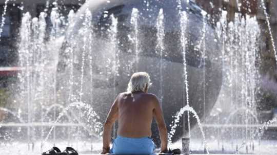 Muž sa ochladzuje vo fontáne pred Prezidentským palácom v Bratislave.