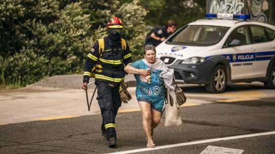 Hasič pomáha pri evakuácii obyvateľov počas rozsiahleho požiaru v chorvátskej obci Grebaštica.