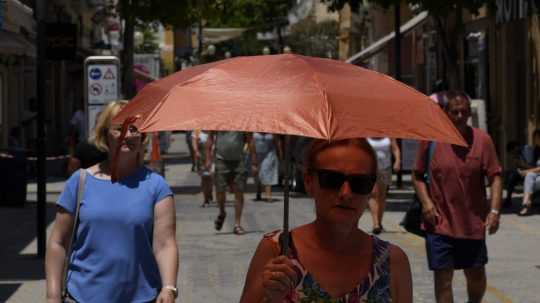 Na ilustračnej snímke sa žena chráni dáždnikom počas horúčav.
