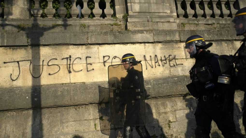 Policajná hliadka prechádza okolo graffiti s nápisom "Spravodlivosť pre Nahela".