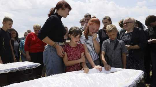 Deti plačú pri rakvách 14-ročných dvojičiek, ktoré zahynuli pri ruskom raketovom útoku na reštauráciu RIA Pizzeria v Kramatorsku.