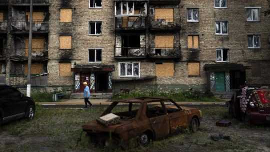 Obyvateľ kráča okolo obytnej budovy ťažko poškodenej po ruských útokoch v meste Irpiň.