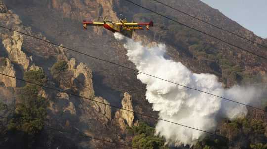 Lietadlo zhadzuje vodu na lesný požiar.