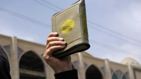 Na snímke žena drzí v ruke Korán