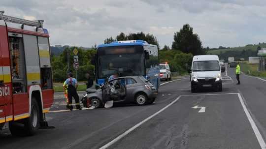 Na snímke poškodený autobus a osobné auto a záchranári