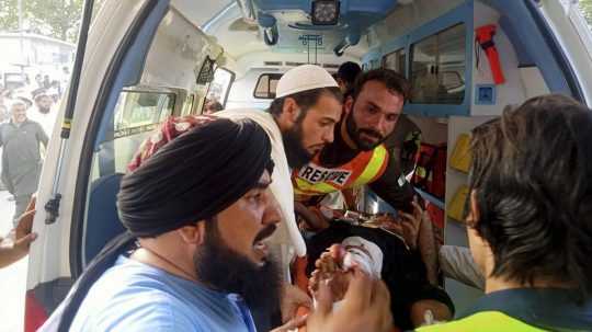 Záchranári nakladajú do sanitky zraneného muža po výbuchu bomby na politickom zhromaždení islamistickej strany v meste Chár v regióne Bádžaur na severozápade Pakistanu.