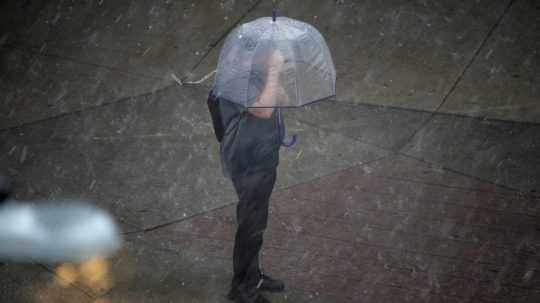 muž s dáždnikom počas silného dažďa