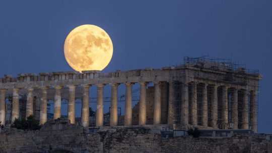 Na snímke mesiac vychádza na oblohe v gréckych Aténach.