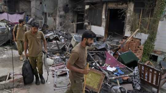 Policajti kráčajú oklolo domov, ktoré zničili rozvášnený moslimský dav v kresťanskej štvrti.