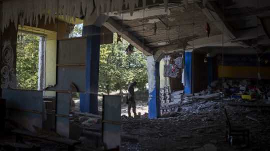 Ukrajinský vojak stojí v tanečnej sále, ktorú predtým bombardovali ruské sily.
