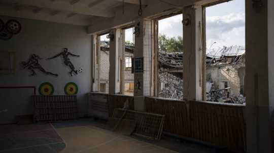 Zničenú školskú knižnicu vidieť cez rozbité okná telocvične v Kupiansku.