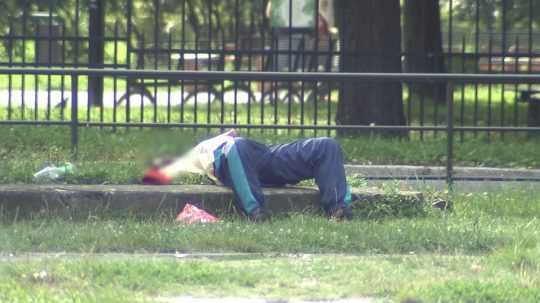 bezdomovec leží na zemi v parku