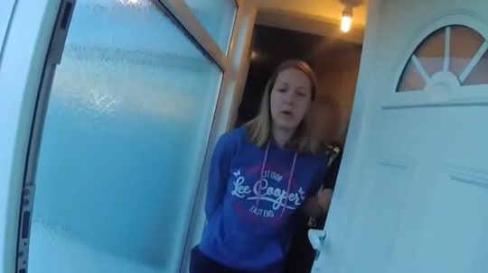 Na snímke obvinenú ženu vyprevádza z domu polícia.