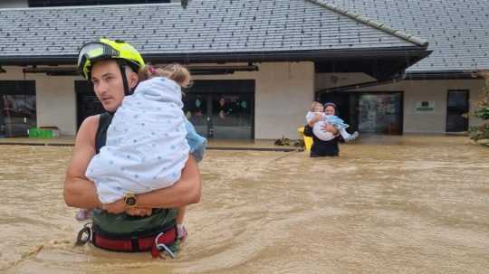 Hasič pomáha s evakuáciou detí zo zaplaveného domu.