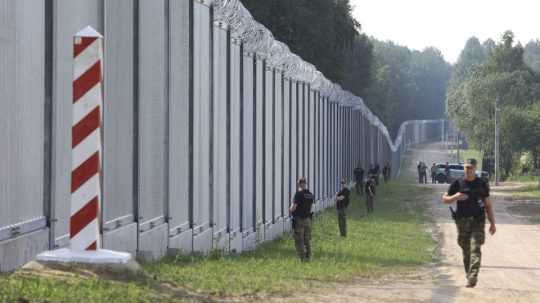 Na archívnej snímke z 30. júna 2022 príslušníci poľskej pohraničnej stráže hliadkujú pozdĺž nového železného múru na hraniciach medzi Poľskom a Bieloruskom.