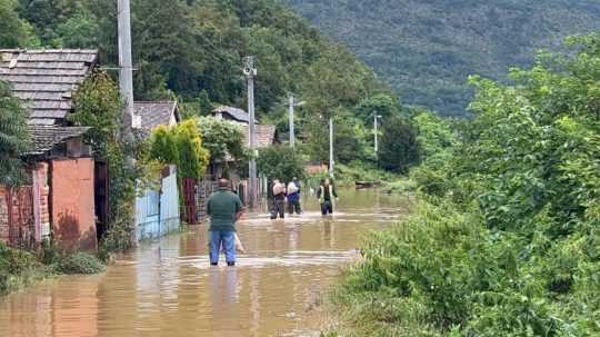 obyvatelia sa brodia vodou, ktorá zaplavila ulice obce.