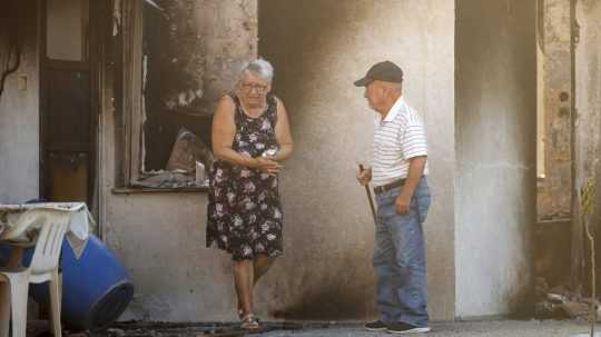 Na snímke starší manželia pri zhorenom dome.