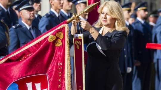 Zuzana Čaputová pripína stuhu na bojovú zástavu.