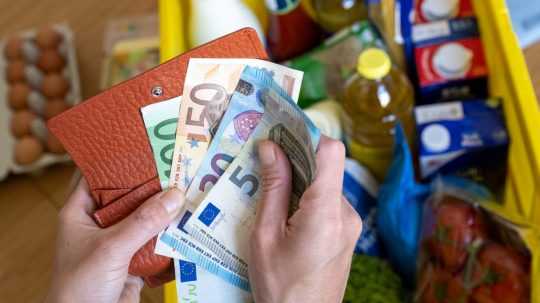 Na snímke žena drží v rukách eurové bankovky nad nákupom v meste.