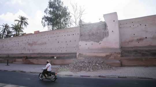 Muž prechádza okolo poškodenej steny historickej Mediny v Marakéši.
