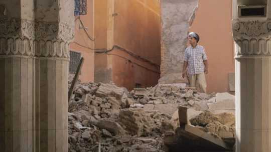 Muž prechádza troskami budovy po zemetrasení v Maroku.