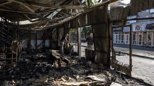 Ľudia odstraňujú trosky na zničenom trhovisku po ostreľovaní ukrajinského mesta Kosťantynivka 7. septembra 2023.