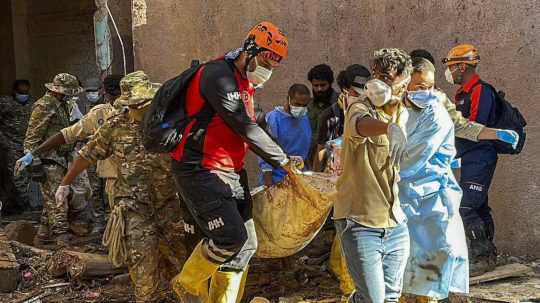 Záchranári vynášajú telo obete ničivých záplav v líbyjskom meste Derna.