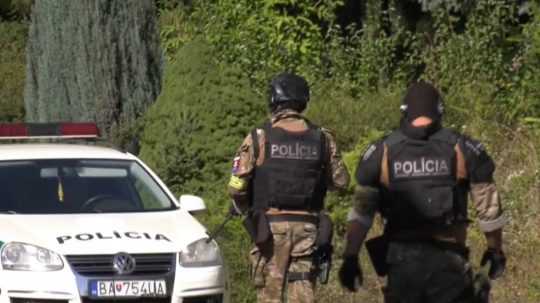 Na snímke policajti v pozadí policajné auto.