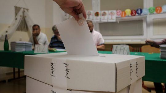 volička vhadzuje obálku s hlasovacím lístkom do volebnej schránky.