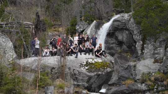 skupina turistov stojí na skale neďaleko vodopádu vo Vysokých tatrách
