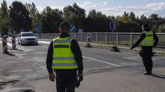 Českí policajti zastavujú osobné motorové vozidlo počas náhodnej kontroly na česko-slovenskej hranici.