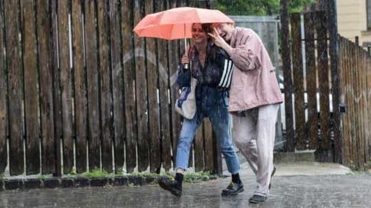 Na snímke dvojica s dáždnikom počas silného dažďa.