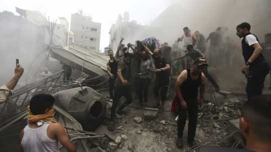 Palestínčania vynášajú mŕtve telo z trosiek budovy po izraelskom leteckom útoku.