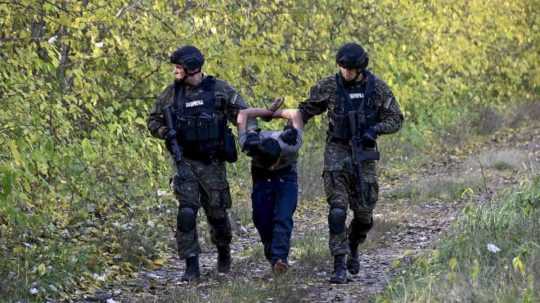 Policajti zadržiavajú migranta pri hraniciach medzi Srbskom a Maďarskom.