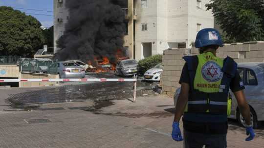 Horiace autá na parkovisku pri obytnom dome po tom, ako ich zasiahli rakety vystrelené z pásma Gazy v izraelskom meste Aškelon 7. októbra 2023.