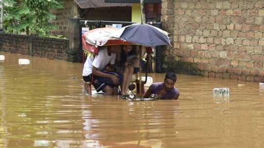 Na snímke sa muž na rikši brodí zaplavenou ulicou.