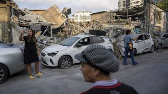 Izraelčania skúmajú trosky budovy deň po raketovom úroku z pásma Gazy, v Tel Avive 8. októbra 2023.