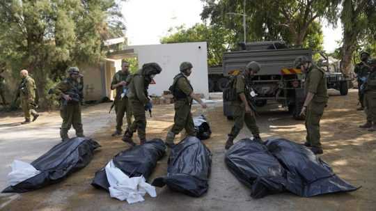 Na snímke vojaci pri mŕtvych obetiach útoku na Izrael