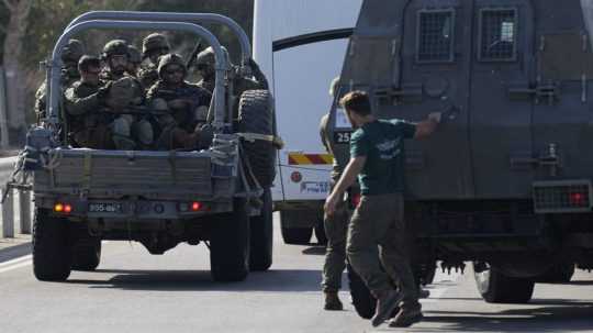 Izraelskí vojaci smerujú na vojenskom aute k horiacemu miestu po raketovom útoku z pásma Gazy na juhu Izraela.