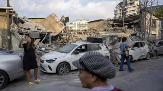 Izraelčania skúmajú trosky budovy deň po raketovom úroku z pásma Gazy, v Tel Avive.