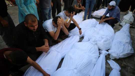 Pozostalí sa zhromaždili okolo tiel obetí izraelských útokov pred márnicou v pásme Gazy.
