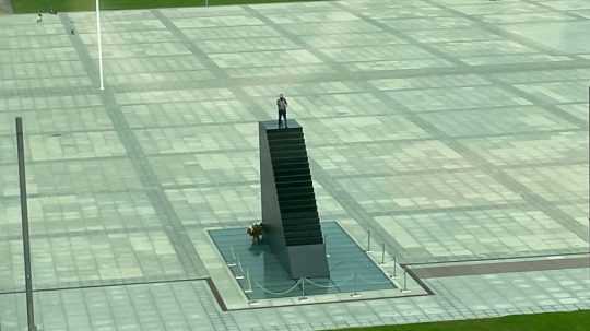 Muž stojí na pamätníku vo Varšave.