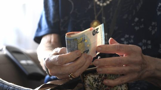Dôchodkyňa na snímke drží eurobankovky.